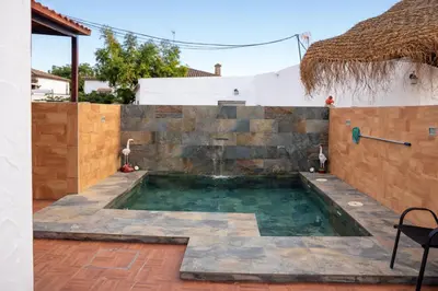 a swimming pool in a backyard with a stone wall at Chalet 2 dormitorios con piscina privada in Conil de la Frontera
