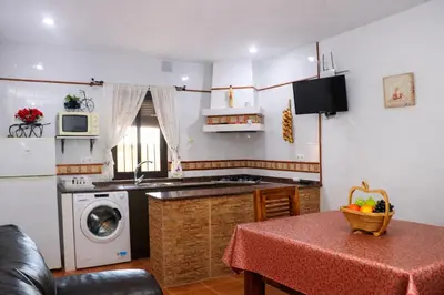 a kitchen with a table and a kitchen with a washing machine at Chalet 2 dormitorios con piscina privada in Conil de la Frontera