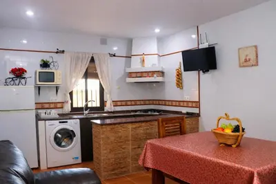 a kitchen with a table and a stove and a microwave at Chalet 2 dormitorios con piscina privada in Conil de la Frontera