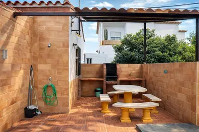 a patio with a table and benches on a brick wall at Chalet 2 dormitorios con piscina privada in Conil de la Frontera