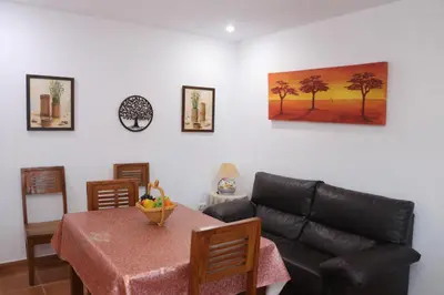 a living room with a table and a couch at Chalet 2 dormitorios con piscina privada in Conil de la Frontera