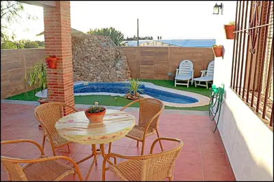 a patio with a table and chairs and a pool at Chalet acogedor con piscina in Conil de la Frontera