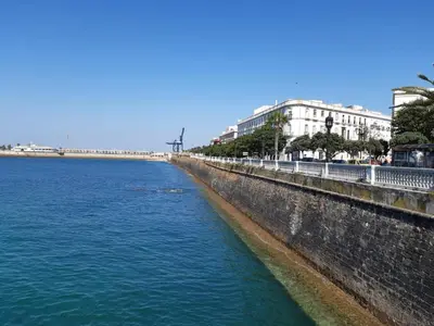 a body of water next to a wall with buildings at Ático Baños del Carmen in Cádiz