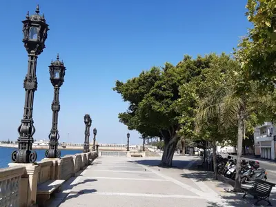 a sidewalk with street lights next to the water at Ático Baños del Carmen in Cádiz