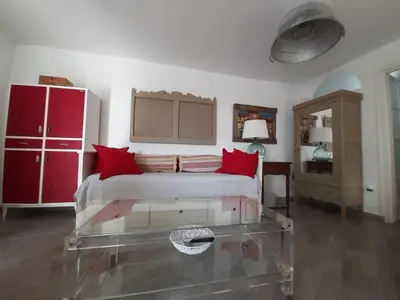 a bedroom with a bed with red pillows and a glass table at Ático Baños del Carmen in Cádiz