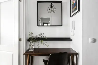a mirror on a wall above a wooden table with a chair at Apartamento San Juan, Parking privado in Jerez de la Frontera