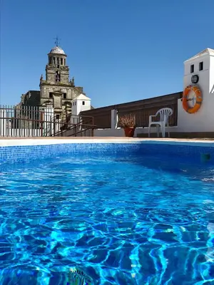 a swimming pool in front of a building with a tower at Apartamento San Juan, Parking privado in Jerez de la Frontera