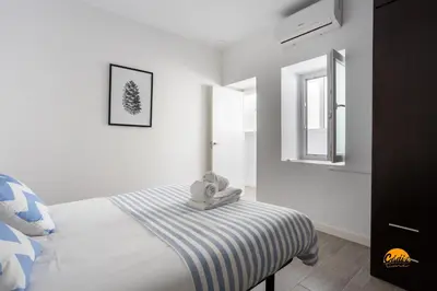 a white bedroom with a bed and a mirror at Atico Catedral by Cadiz Time in Cádiz