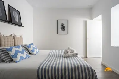 a bedroom with a large bed with blue and white pillows at Atico Catedral by Cadiz Time in Cádiz