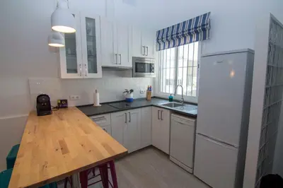 a kitchen with a wooden table and a white refrigerator at Casa Izaro in Sanlúcar de Barrameda