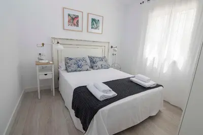 a white bedroom with a bed with towels on it at Casa Izaro in Sanlúcar de Barrameda