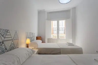 a white bedroom with two beds and a window at COLON15 Family Home by Cadiz4Rentals in Cádiz