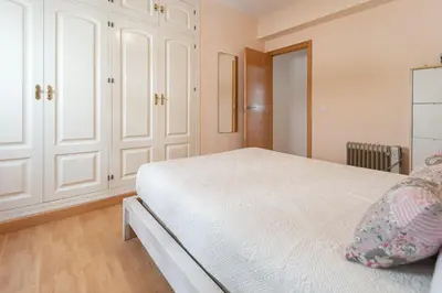 a bedroom with a white bed and white cabinets at Apartamento las Jacarandas de Cadiz in Cádiz
