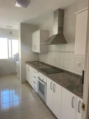 a kitchen with white cabinets and a stove top oven at vistas maravillosas in Chipiona