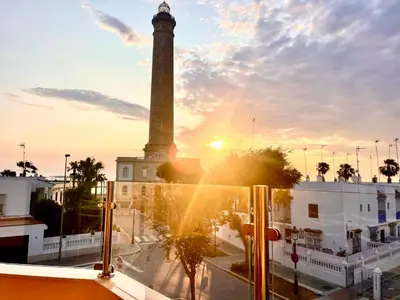 a clock tower in a city with the setting sun at vistas maravillosas in Chipiona