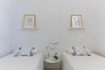 two beds in a room with white walls at Duplex Terraza Rivera Marisco 2 Dormitorios 2 Baños in El Puerto de Santa María