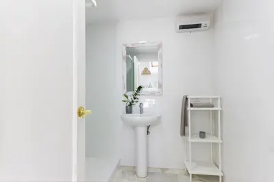 a white bathroom with a sink and a mirror at Duplex Terraza Rivera Marisco 2 Dormitorios 2 Baños in El Puerto de Santa María