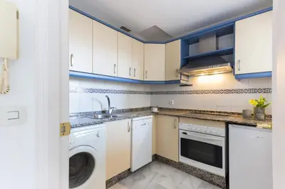 a kitchen with white cabinets and a washer and dryer at Duplex Terraza Rivera Marisco 2 Dormitorios 2 Baños in El Puerto de Santa María