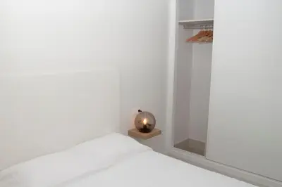 a white bedroom with a bed and a small lamp at El mirador de Ancha in Cádiz