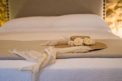 a hat on a bed with a dress and roses at CASA PACO - Casita con Encanto in Medina Sidonia