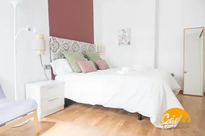 a white bedroom with a white bed and a chair at Apartamento Caleta - FREE PARKING by Cadiz Time in Cádiz