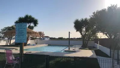 a swimming pool with two chairs and a sign next to a fence at Villas Santa Ana in Conil de la Frontera