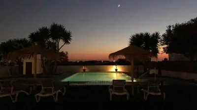 a swimming pool with chairs and a sunset at Villas Santa Ana in Conil de la Frontera