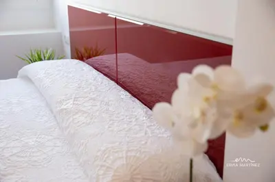 a bed with a mirror and some white flowers at Apartamento Cañadilla MRZ Rentals in El Puerto de Santa María
