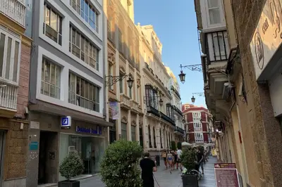 a man walking down a city street with buildings at El mirador de Ancha in Cádiz
