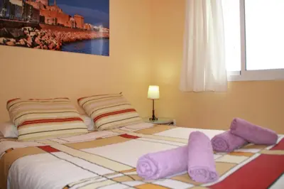 a bedroom with a bed with purple pillows on it at DescubreHome Playa de la Caleta in Cádiz