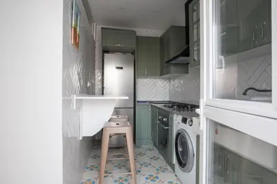 a small kitchen with green cabinets and a washing machine at El ático de los mosaicos in Cádiz