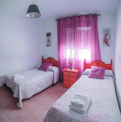 two beds in a room with pink curtains at La Guareña in Chiclana de la Frontera