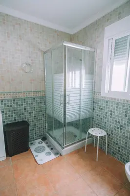 a glass shower in a bathroom with a stool at La Guareña in Chiclana de la Frontera