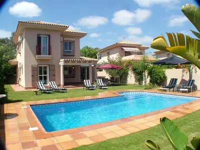 a house with a swimming pool in front of a house at VILLA FLAMINGO in Chiclana de la Frontera