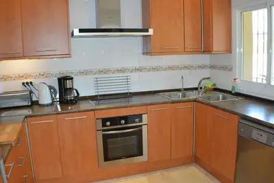 a kitchen with wooden cabinets and stainless steel appliances at VILLA FLAMINGO in Chiclana de la Frontera