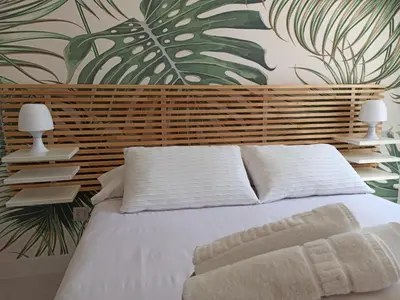 a bedroom with a white bed with a tropical wallpaper at Viña 41 in Cádiz