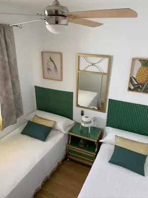 two twin beds in a room with a mirror at ATICO LA ILUSION CON PARkING in Sanlúcar de Barrameda