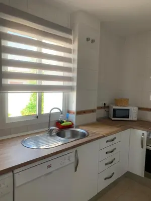 a kitchen with a sink and a microwave at ATICO LA ILUSION CON PARkING in Sanlúcar de Barrameda