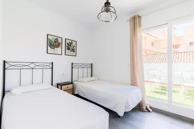 two beds in a white room with a window at Sanlúcar Olehousing in Sanlúcar de Barrameda