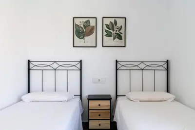 two beds in a room with white walls at Sanlúcar Olehousing in Sanlúcar de Barrameda