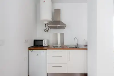 a white kitchen with a sink and a microwave at Sanlúcar Olehousing in Sanlúcar de Barrameda