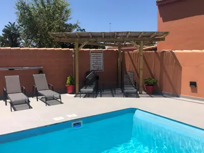 a swimming pool with chairs and a wooden pergola at Loft con Piscina ADULTS ONLY in Chiclana de la Frontera