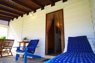 a porch with a bed and two chairs on a patio at Villa Ada con Piscina, Jardin y Parking 9,3 in Chiclana de la Frontera