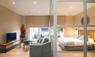 a woman walking through a bedroom with a bed and a tv at Terraza Playa de Cádiz 1 Ha Apartment in Cádiz