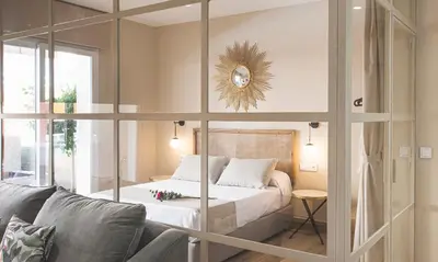 a bedroom with a bed and a couch and a mirror at Terraza Playa de Cádiz 1 Ha Apartment in Cádiz