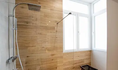 a shower in a bathroom with a wooden wall at Terraza Playa de Cádiz 2 Ha Apartment in Cádiz