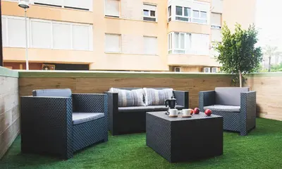 a patio with two chairs and a table and a building at Terraza Playa de Cádiz 2 Ha Apartment in Cádiz
