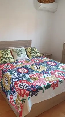a bed with a colorful comforter and pillows on it at Apartamento Helena in Rota