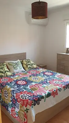 a bed with a colorful comforter on it in a bedroom at Apartamento Helena in Rota