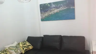 a black couch in a living room with a picture on the wall at Apartamento Helena in Rota